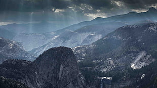 aerial photography of crepuscular rays over mountains during daytime