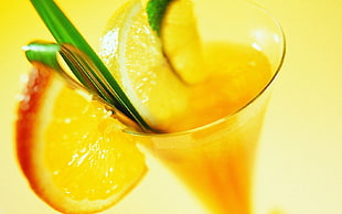 orange juice in clear drinking glass with slice of orange