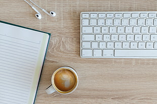 Apple Magic Keyboard beside white ceramic mug and white lined paper