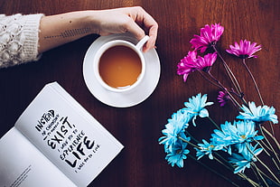 top view photograph of flowers, cup, and book