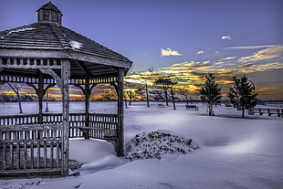 gray wooden gazebo covered with snow