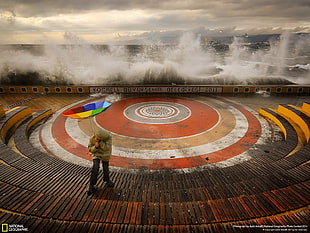 person standing on stadium holding rainbow inverted umbrella digital wallpaper HD wallpaper