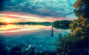 landscape photography of U.S.A. flag near body of water during golden hour