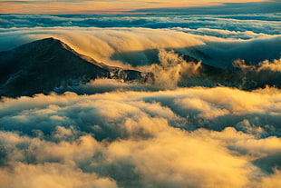 high-rise photography of thick clouds and mountain during golden hour