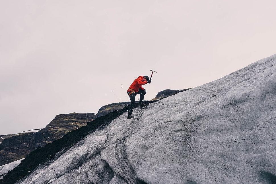 person in red jacket climbing on mountain during daytime HD wallpaper