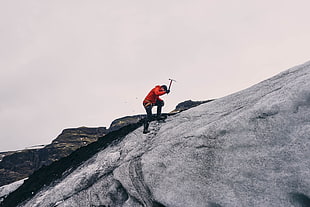 person in red jacket climbing on mountain during daytime HD wallpaper