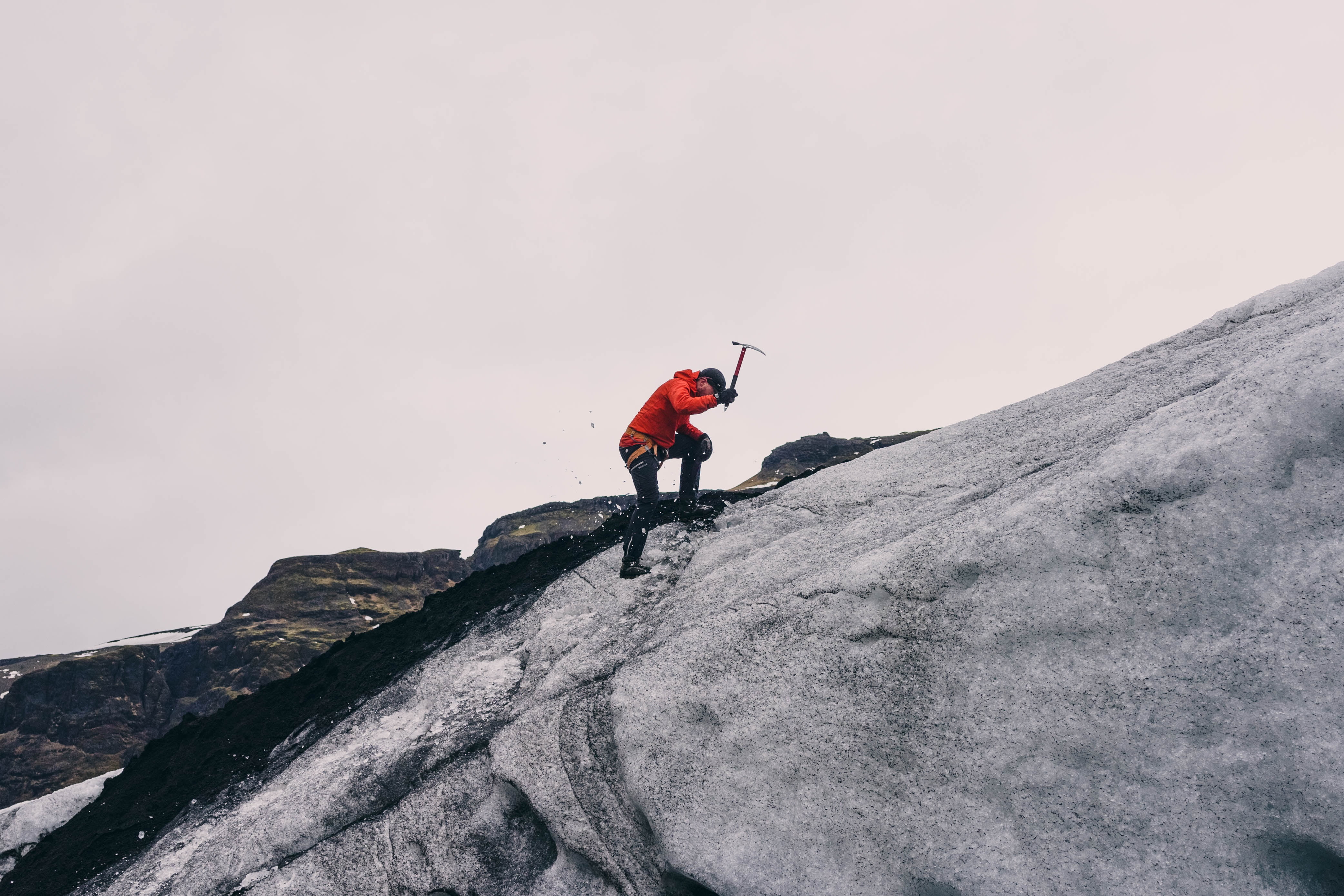 person in red jacket climbing on mountain during daytime