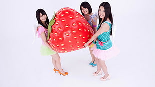 three women holding red strawberry