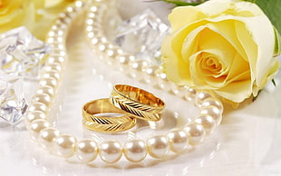 gold-colored bridal ring set near pearl necklace
