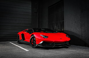 red Lamborghini Aventador parked beside gray concrete wall HD wallpaper