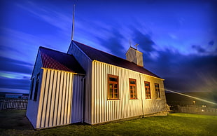 white wooden house on green lawn grass under blue sky during twilight