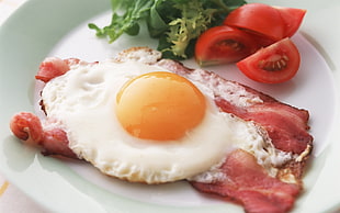 served sunny egg, sliced tomatoes and pork on white ceramic plate
