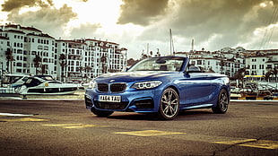 blue BMW convertible couple in front of white concrete buildings