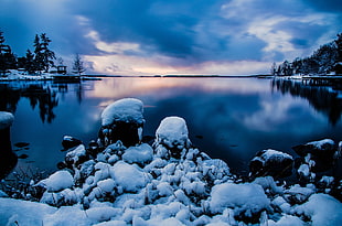 landscape photo of river surrounded by snow beside mountain during dawn