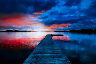 boat dock station in front of body of water under red and blue sky