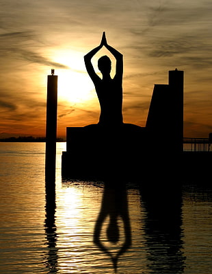 silhouette of person doing yoga pose during sunset