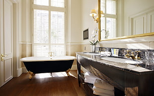black and white ceramic bathtub near window inside the room