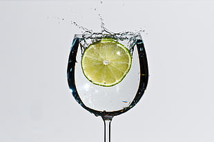 close up photo of sliced lemon splashed in wine glass