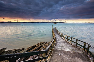brown wooden dock beside ocean during sunset, herne