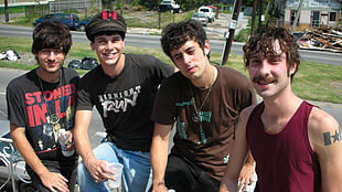 four men poses near green grass lawn