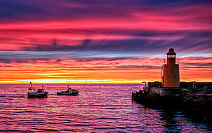 white lighthouse over body of water with floating boats during golden hour, sea, sky, boat, lighthouse