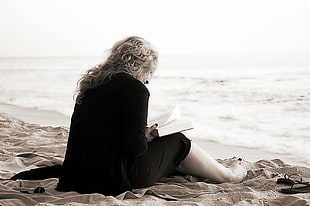woman near a seashore reading a book