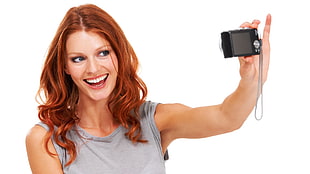 woman wearing gray tank top holding black compact camera