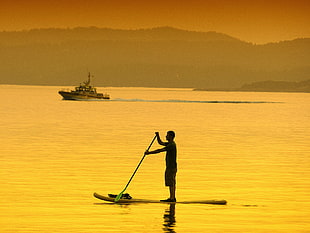silhouette photo of man on kayak with padded