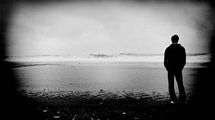 man in black dress shirt and black pants standing beside sea shore
