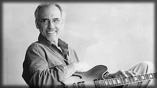 man holding Les Paul guitar grayscale photo