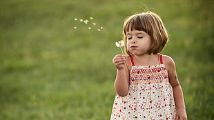 girl blowing white flower
