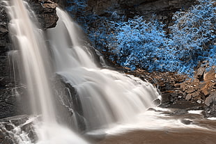 waterfalls between big rocks and trees HD wallpaper