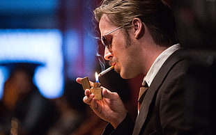 shallow focus photography of man wearing formal coat lighting a cigarette