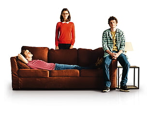 man lying on sofa beside man sitting on armrest against woman standing HD wallpaper