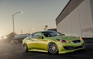 green sports coupe near grey and white wall