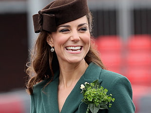 close-up photography of woman wearing black cap and green blazer smiling