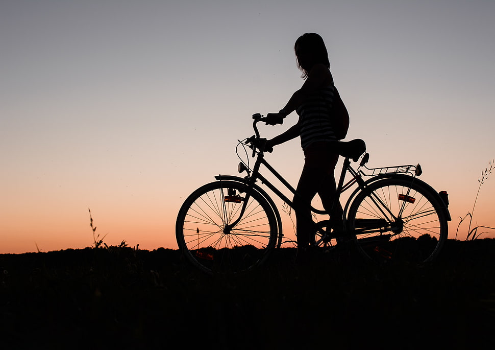 silhouette of woman holding bicycle during sunset HD wallpaper
