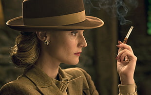 woman wearing brown hat holding cigarette stick