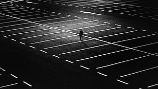 silhouette of person standing on parking lot in grayscale photography