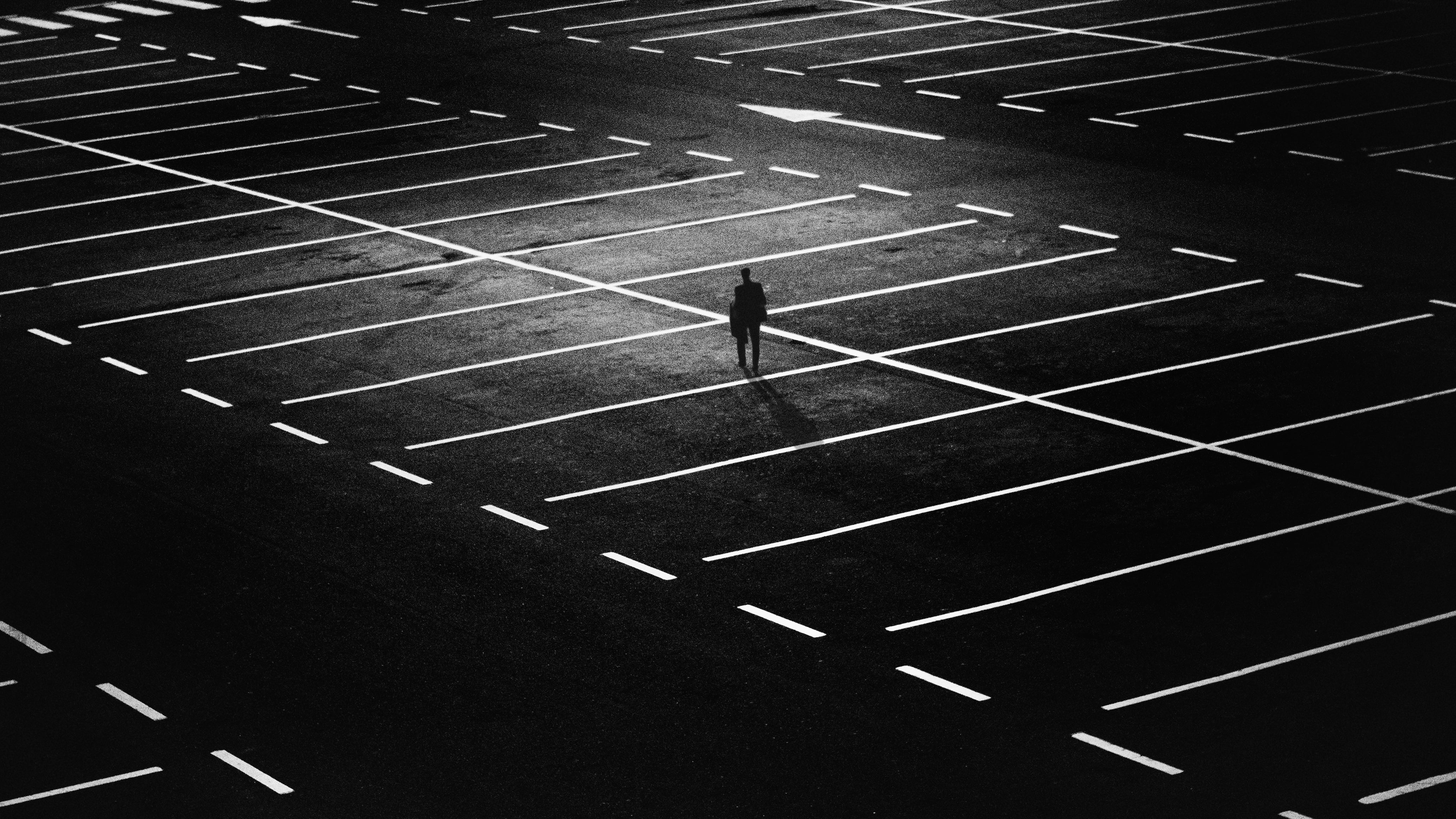 silhouette of person standing on parking lot in grayscale photography