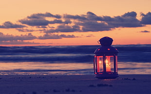 photography of black candle lantern during sunset