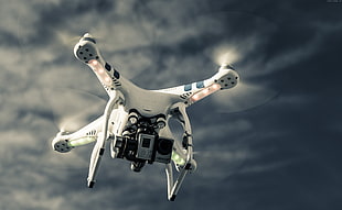 white and black quad copter drone flying