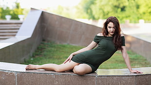 woman wearing mini dress and sitting on concrete surface