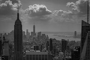 grayscale photograph of city buildings under cloudy sky
