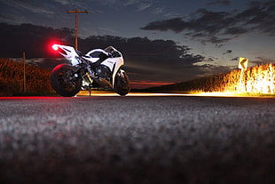 photo of white sports bike on roadway during nightime