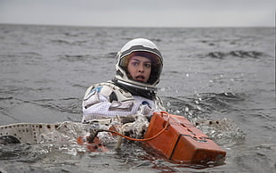 woman astronaut on body of water while holding orange case front the Martian movie still