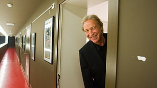 man wearing black suit jacket peaking in door way