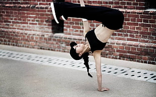 woman in black sports bra and black pants showing hand stand