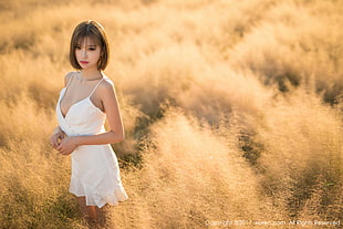 woman in white spaghetti strap dress standing on brown grassfield