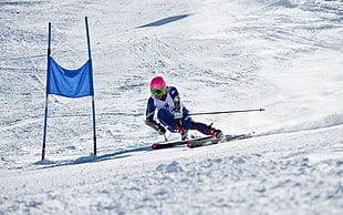 man wearing blue and white snow ski protective gears riding on snow skis and holding ski poles